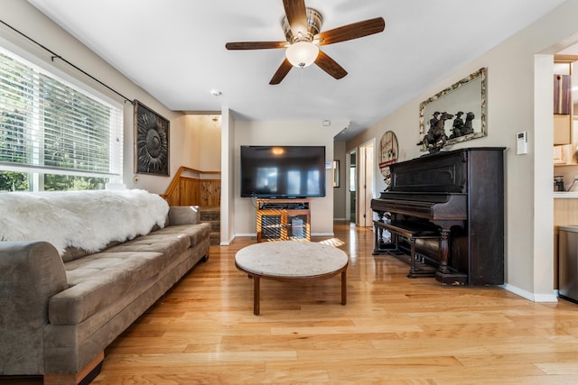 living area featuring ceiling fan, light wood-style floors, and baseboards