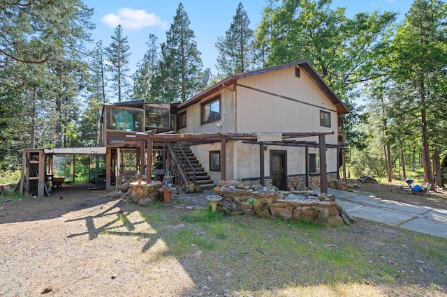 rear view of property featuring stairway and a sunroom