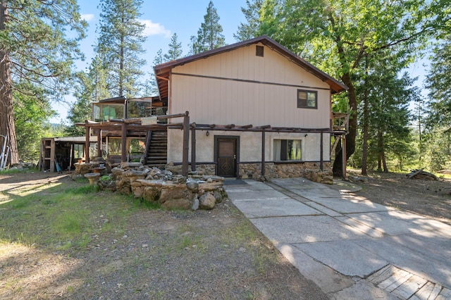 exterior space featuring stone siding, a deck, and stairs