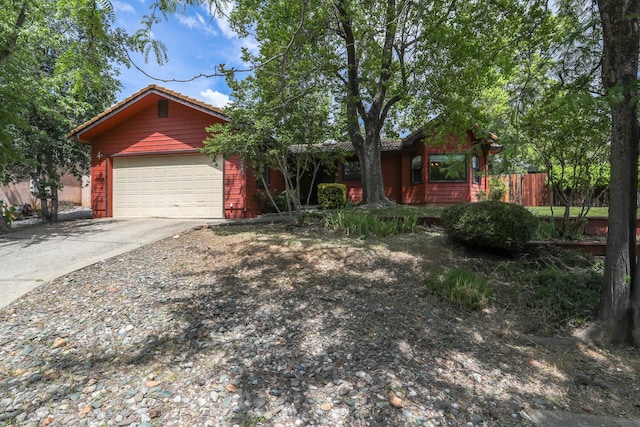 ranch-style house featuring concrete driveway, fence, and a garage