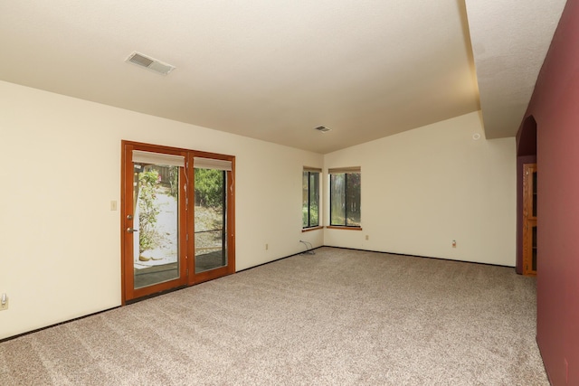 carpeted empty room featuring vaulted ceiling