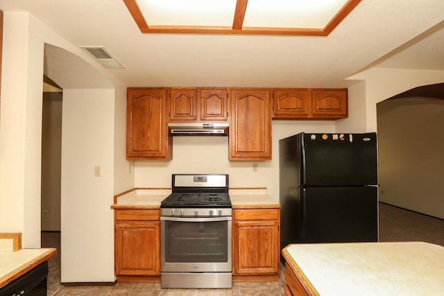 kitchen with stainless steel range with gas stovetop, freestanding refrigerator, light countertops, and under cabinet range hood