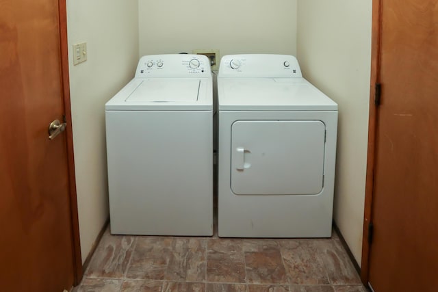 washroom with washer and dryer and stone finish flooring