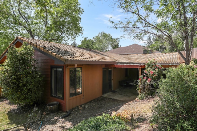 rear view of house with a tile roof and a patio