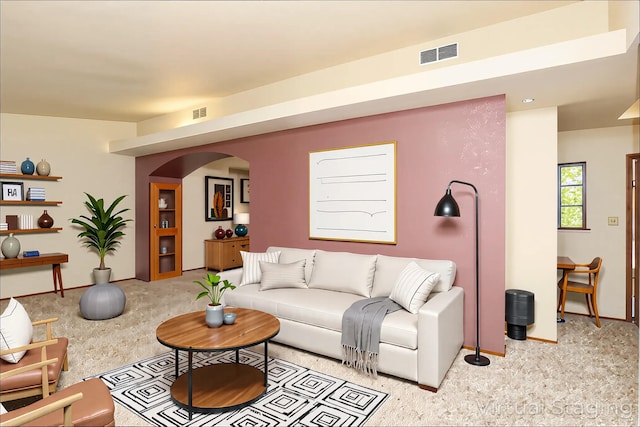 carpeted living room with arched walkways and baseboards