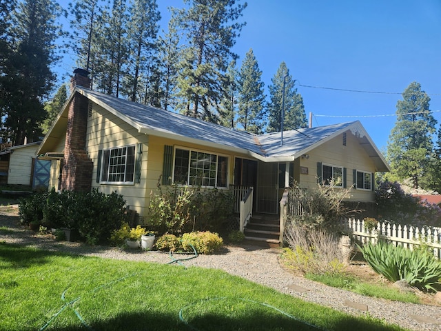 ranch-style home with a chimney and fence