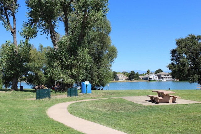 surrounding community featuring a lawn, a patio area, and a water view