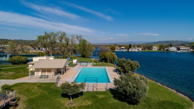 community pool with a water view, a patio, and a yard