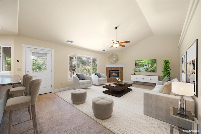 living area featuring lofted ceiling, ceiling fan, a high end fireplace, and visible vents