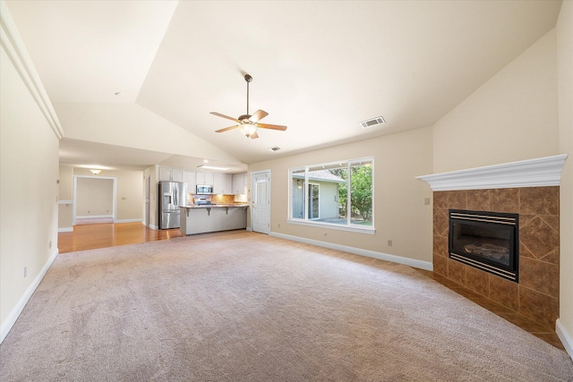 unfurnished living room featuring visible vents, vaulted ceiling, ceiling fan, light carpet, and baseboards