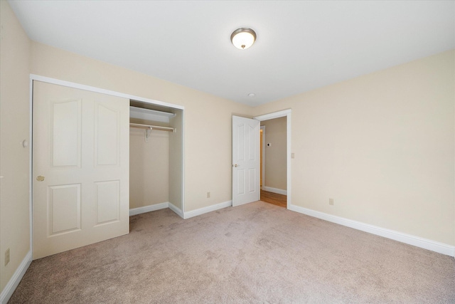 unfurnished bedroom featuring baseboards, a closet, and light colored carpet