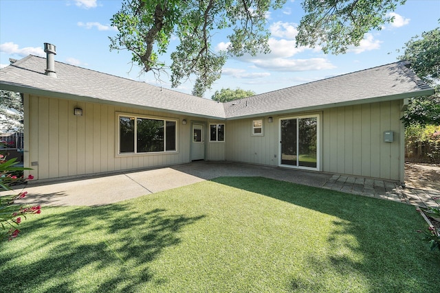 back of property featuring a lawn, a patio area, and a shingled roof