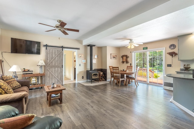 12637 Ivie Ln, Old Station, CA 96071 - living room featuring ceiling fan, wood finished floors, a barn door, a wood stove, and baseboards