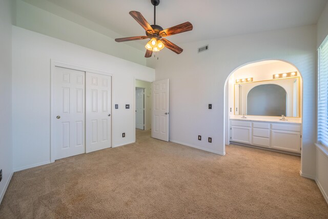 2529 Candlewood Dr, Redding, CA 96003 - unfurnished bedroom featuring light carpet, a closet, connected bathroom, arched walkways, and ceiling fan