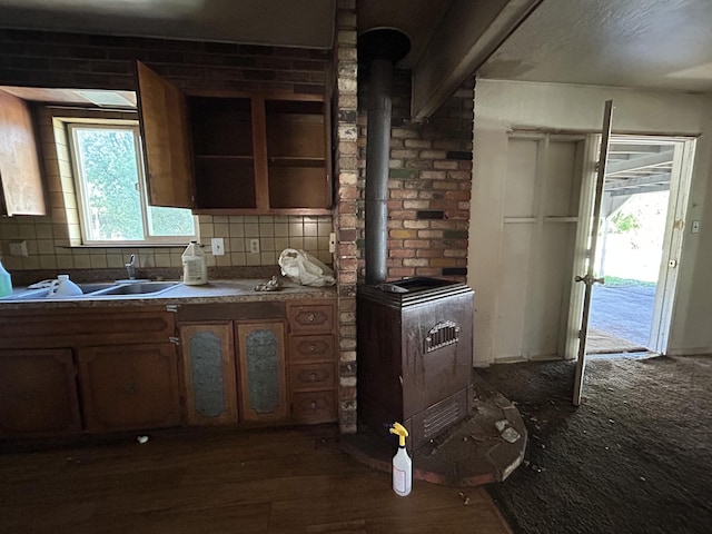 kitchen with a wealth of natural light, a wood stove, dark wood finished floors, and tasteful backsplash