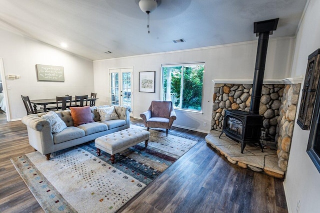 living room featuring wood finished floors, a wood stove, baseboards, lofted ceiling, and a ceiling fan