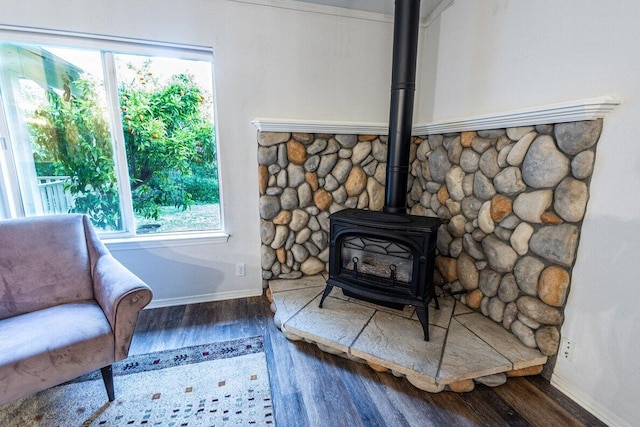 detailed view of a wood stove, wood finished floors, and baseboards