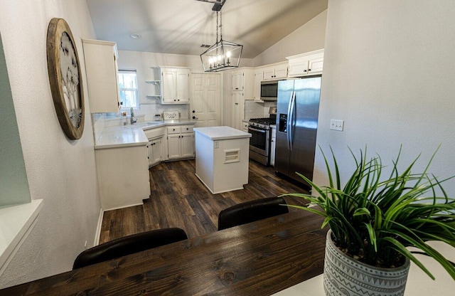 kitchen with appliances with stainless steel finishes, a center island, dark wood-style flooring, light countertops, and a sink