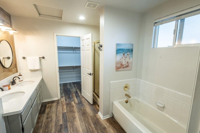bathroom with wood finished floors, a walk in closet, a bath, a shower stall, and recessed lighting