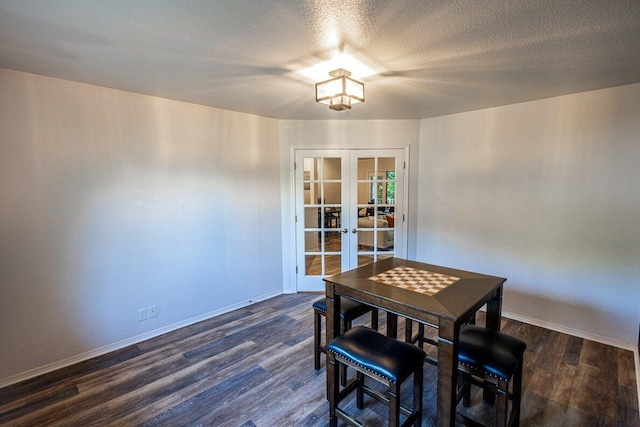 dining space with french doors, dark wood finished floors, baseboards, and a textured ceiling
