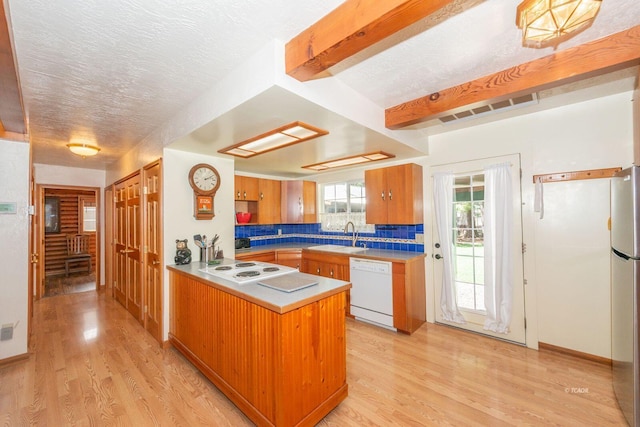 kitchen featuring a peninsula, light wood-style floors, a sink, and white appliances