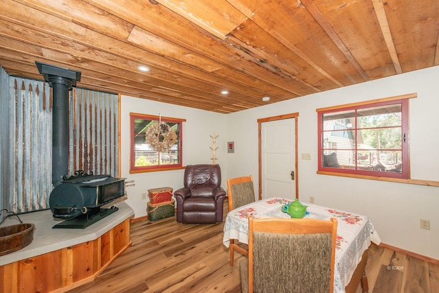 dining area featuring a wood stove, light wood-style floors, baseboards, and recessed lighting