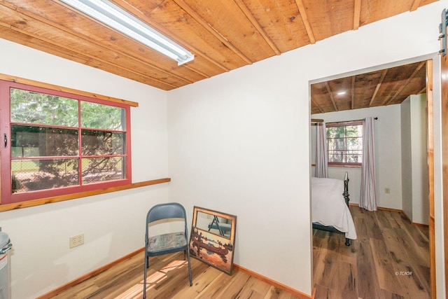 living area with baseboards, wood ceiling, and wood finished floors