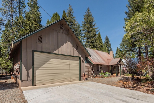 view of front facade with driveway, log exterior, metal roof, a chimney, and board and batten siding