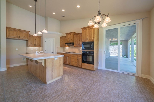 3641 Deuce Way, Redding, CA 96002 - kitchen featuring black appliances, light countertops, a chandelier, under cabinet range hood, and backsplash