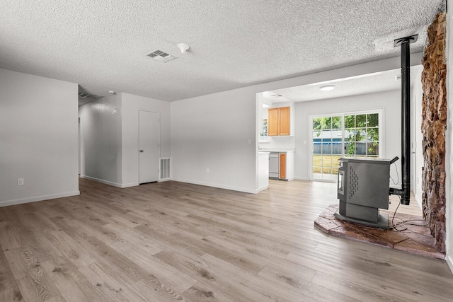 19017 Snowflake Ln, Redding, CA 96003 - unfurnished living room featuring a wood stove, light wood-type flooring, a textured ceiling, and baseboards