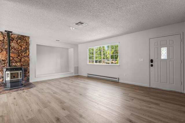 19017 Snowflake Ln, Redding, CA 96003 - unfurnished living room featuring a baseboard heating unit, wood finished floors, a textured ceiling, a wood stove, and baseboards