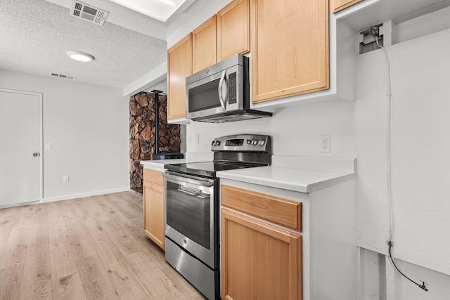 19017 Snowflake Ln, Redding, CA 96003 - kitchen with stainless steel appliances, a textured ceiling, light countertops, light brown cabinetry, and light wood finished floors