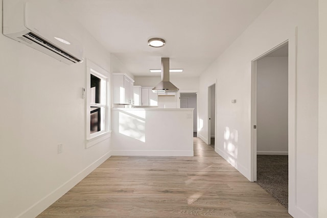 1048 Franklin St, Red Bluff, CA 96080 - kitchen featuring a peninsula, light wood finished floors, a wall mounted air conditioner, island range hood, and white cabinets