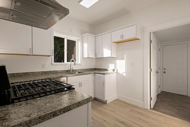 1048 Franklin St, Red Bluff, CA 96080 - kitchen featuring exhaust hood, a sink, white cabinetry, dark countertops, and light wood-type flooring