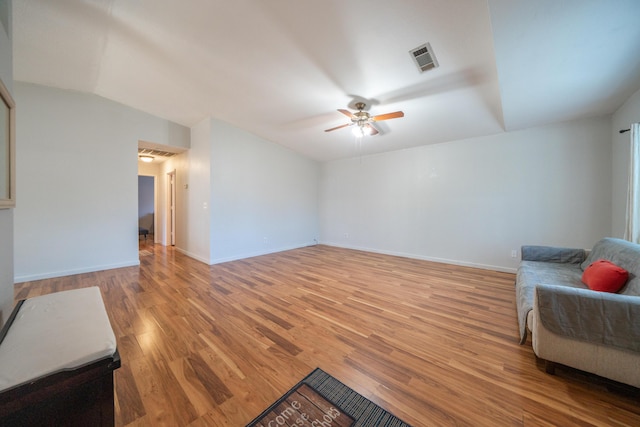 unfurnished living room with light wood-type flooring, ceiling fan, baseboards, and vaulted ceiling