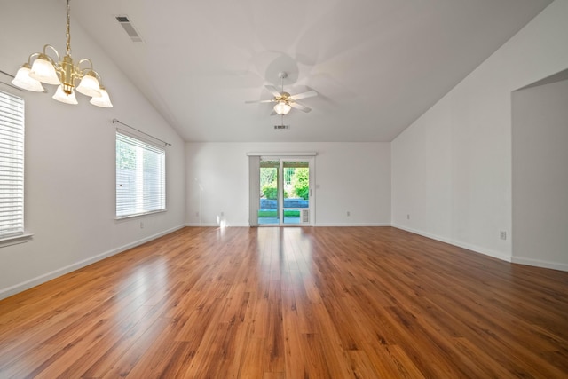 empty room featuring a chandelier, ceiling fan, lofted ceiling, wood finished floors, and baseboards