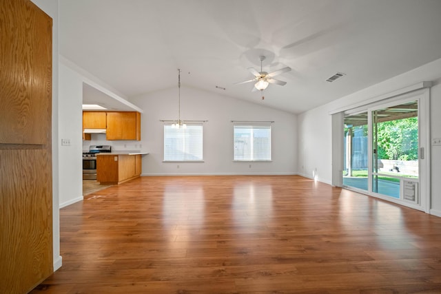 unfurnished living room featuring plenty of natural light, ceiling fan, wood finished floors, vaulted ceiling, and a chandelier