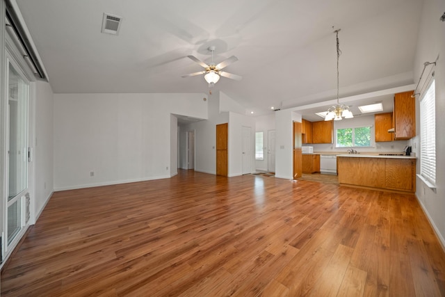 kitchen featuring brown cabinets, open floor plan, light countertops, white appliances, and light wood-style flooring