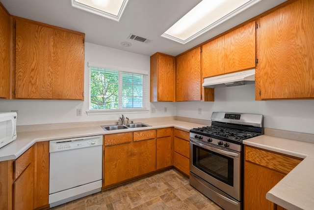 kitchen with white appliances, under cabinet range hood, a sink, light countertops, and brown cabinets