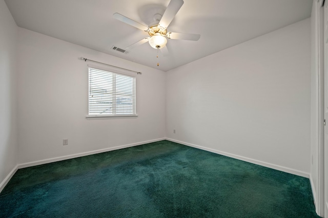 spare room with dark carpet, baseboards, and a ceiling fan