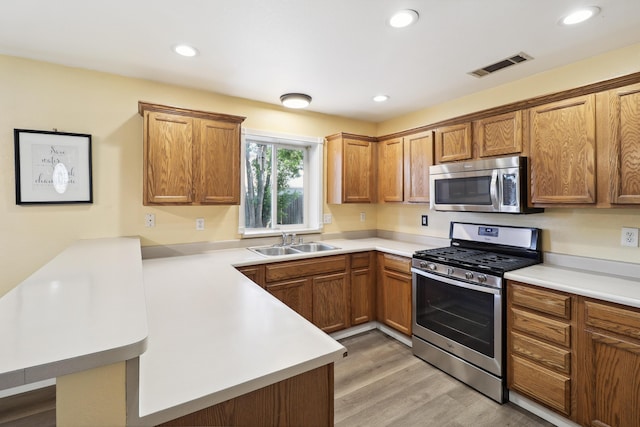 3268 Lyndsey Ln, Anderson, CA 96007 - kitchen featuring stainless steel appliances, a sink, a peninsula, light wood-style floors, and light countertops