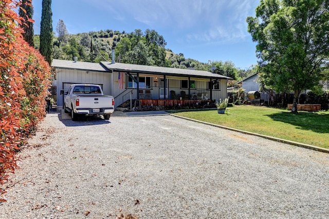 14851 Ravine Rd, Redding, CA 96003 - single story home with covered porch, gravel driveway, a front yard, and an attached garage