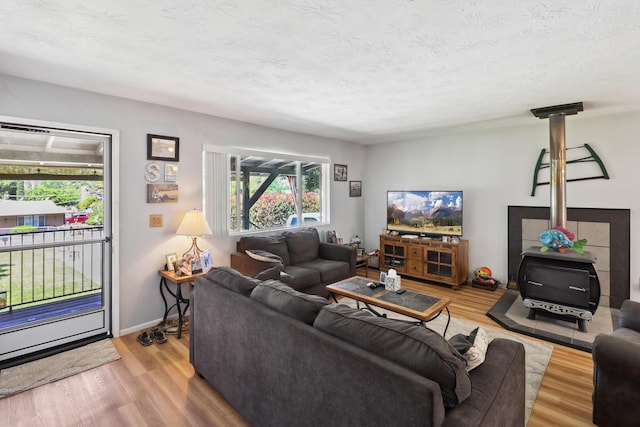 14851 Ravine Rd, Redding, CA 96003 - living room with healthy amount of natural light, wood finished floors, a textured ceiling, a wood stove, and baseboards