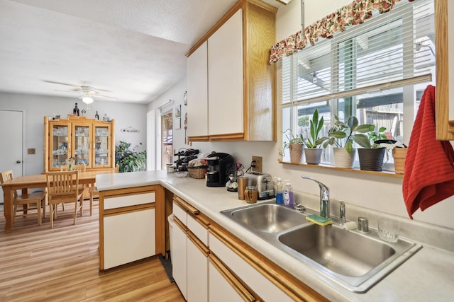 14851 Ravine Rd, Redding, CA 96003 - kitchen featuring a sink, light wood-type flooring, light countertops, a peninsula, and white cabinets