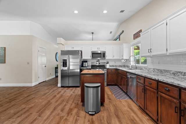 1946 Jeanae Ct, Redding, CA 96002 - kitchen featuring appliances with stainless steel finishes, a sink, vaulted ceiling, backsplash, and a kitchen island