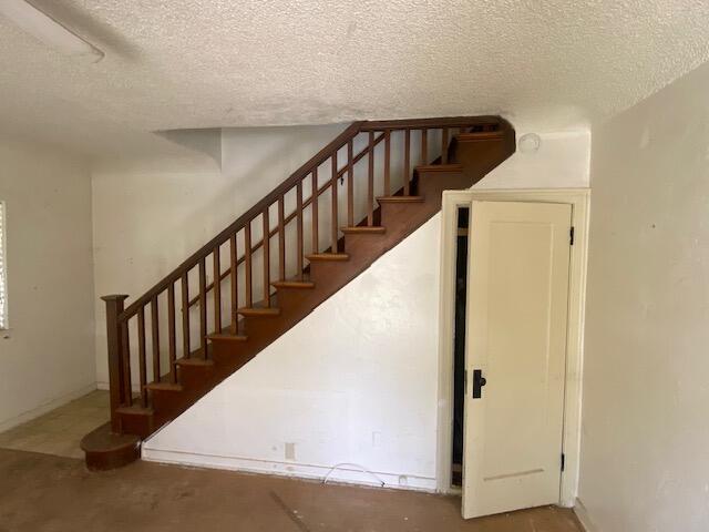 stairway featuring a textured ceiling