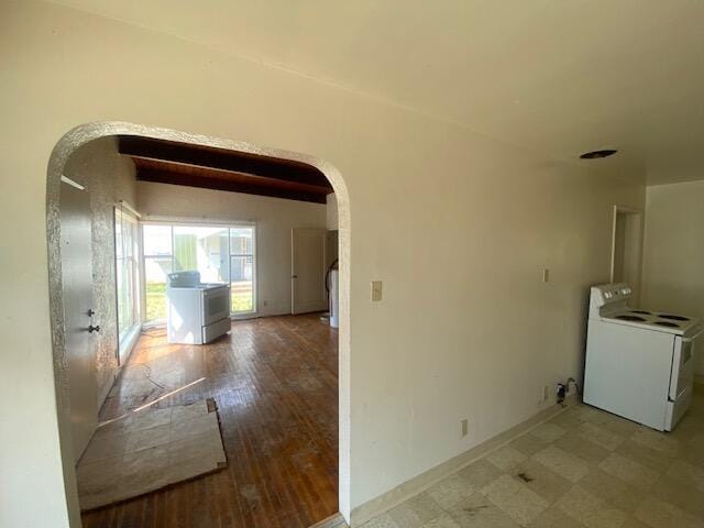 hall featuring washer / clothes dryer, arched walkways, and baseboards