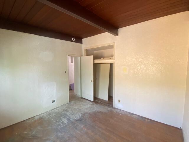 unfurnished room with beamed ceiling, wooden ceiling, and concrete floors