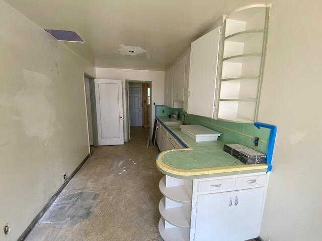 1170-1176 Orange Ave, Redding, CA 96001 - kitchen featuring open shelves, white cabinets, tile counters, and a sink