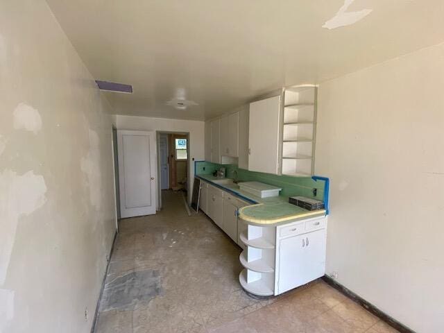 kitchen featuring white cabinets, open shelves, and a sink